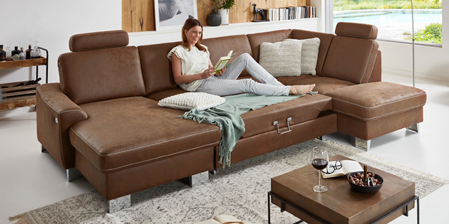 Frau auf braunem Sofa sitzend und lesend, Wohnzimmerdeko