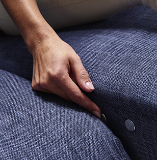 Knopf für motorische Relaxfunktion bei blauem Sofa