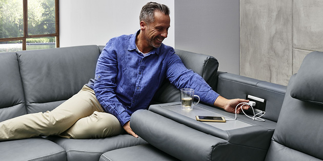 Mann auf Sofa mit integrierter Steckdose